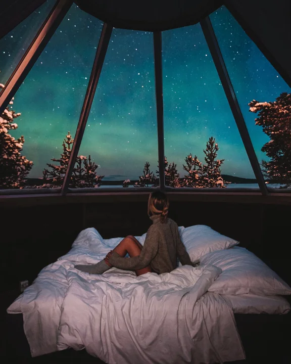 Céu de aurora visto da cama de uma cabana de vidro